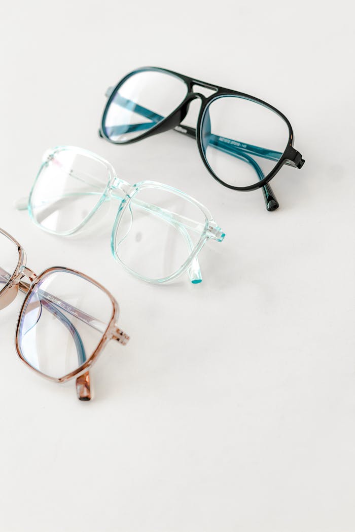 Three pairs of stylish eyeglasses arranged on a white surface, showcasing different frame colors and styles.
